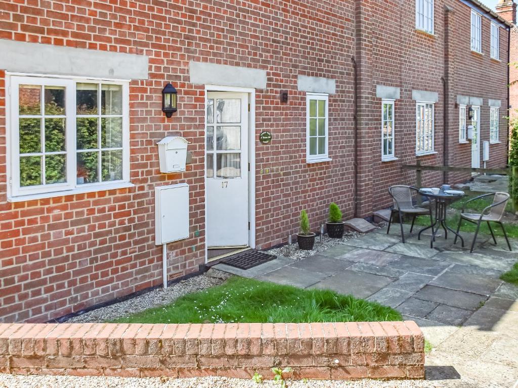 a brick house with a white door and a table and chairs at Coops Nest in Stalham