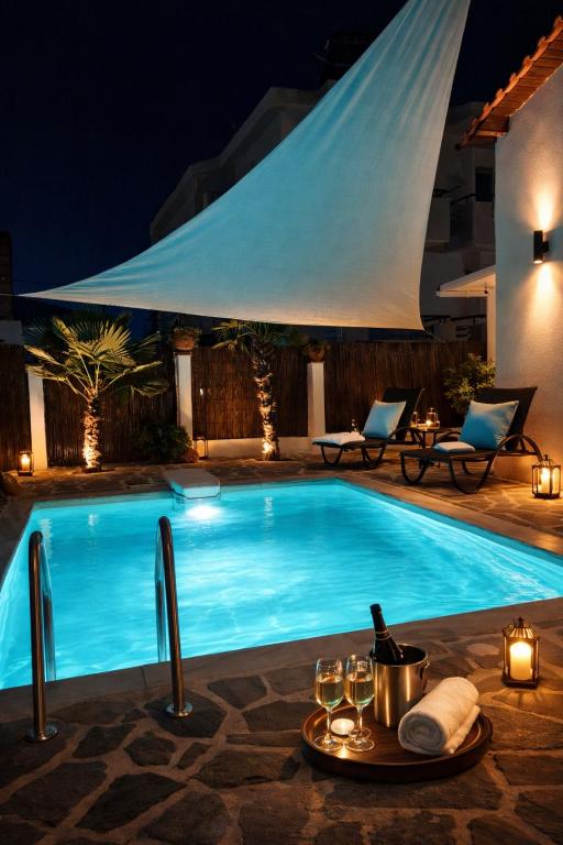 a swimming pool at night with a table with wine glasses at Villa Shada's pool & Jacouzi in Nea Irakleia