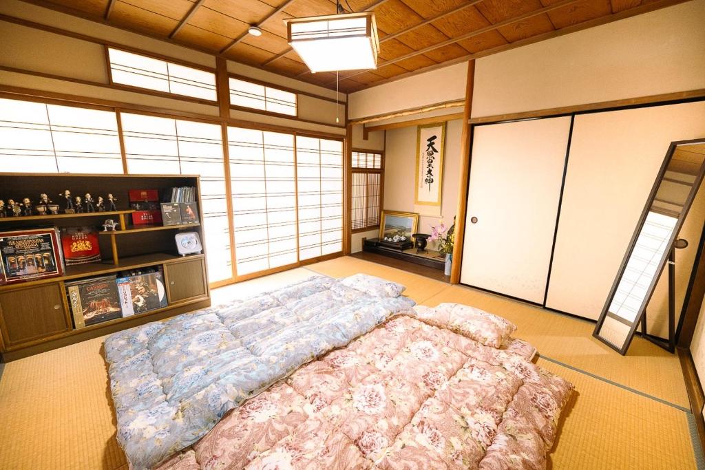 a bedroom with a large bed in a room with windows at 民泊豊久 in Nigō