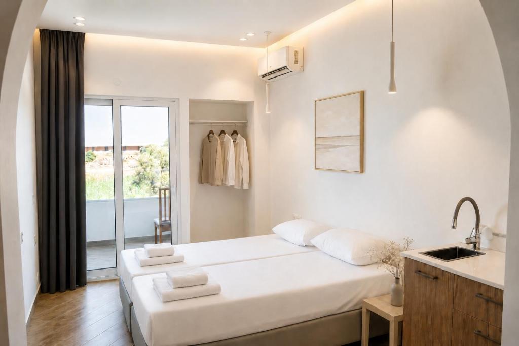 a white bedroom with a large bed and a window at Ela Mare Sea View Apartments in Malia