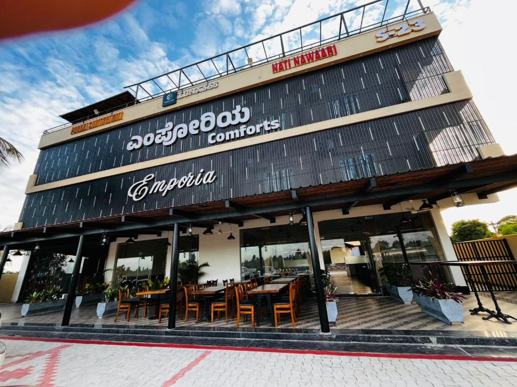 a restaurant with tables and chairs in front of it at Emporia comforts in Devanhalli