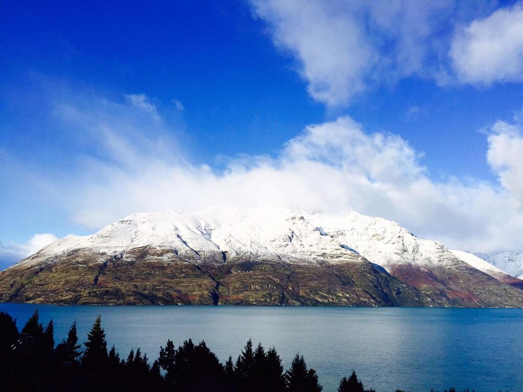 a snow covered mountain sitting on top of a body of water at Queenstown Lakeview Holiday Home-5mins to town in Queenstown