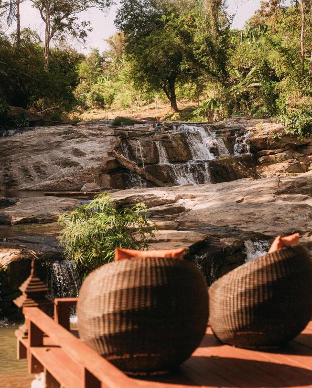 two vases sitting on a bench in front of a waterfall at Sukantara Cascade Resort and Spa in Mae Rim