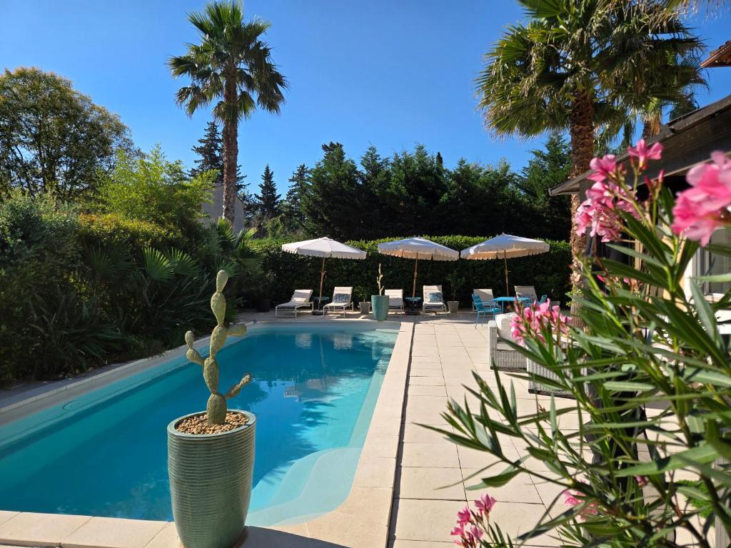 a swimming pool with chairs and umbrellas at La Parenthèse de Villepey in Saint-Aygulf