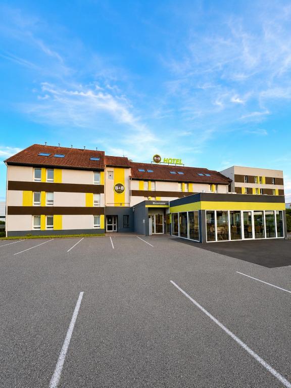 a building with a parking lot in front of it at B&B HOTEL PERPIGNAN Nord Aéroport in Perpignan