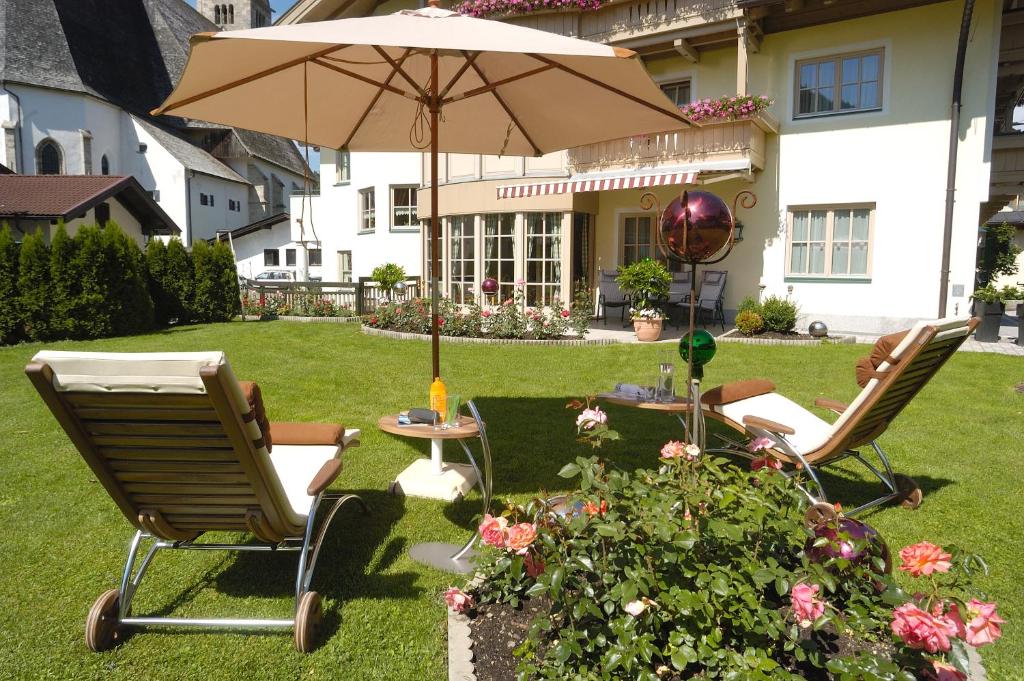 two chairs and a table with an umbrella in a yard at Ferienwohnungen Johanneshof in Maria Alm am Steinernen Meer