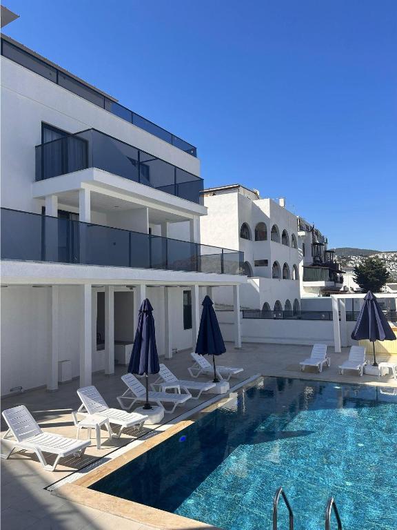 a swimming pool with chairs and umbrellas next to a building at Lumy Suite Hotel Bodrum Gumbet - Private Pool in Bodrum City