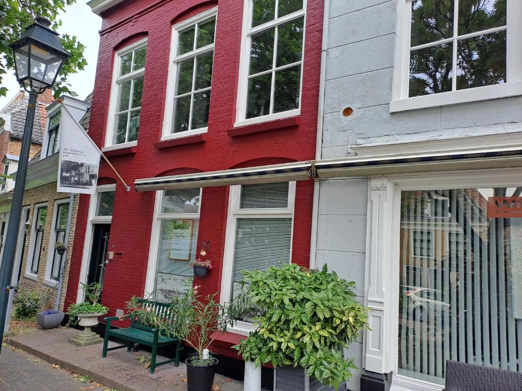 a red house with a green bench in front of it at Het Speijerhuis in Harlingen