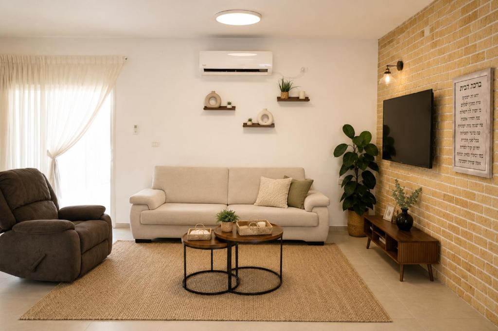 a living room with a couch and a table at סוויטת אריאל - סוויטה משפחתית עם מרפסת בבית שאן in Bet Sheʼan