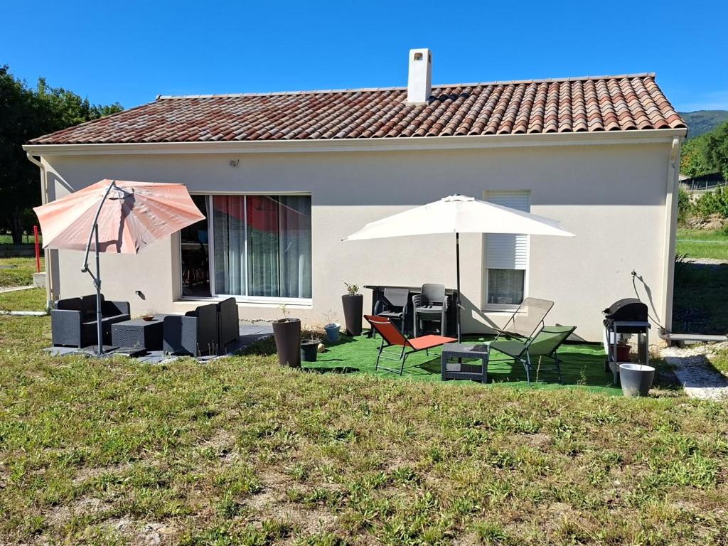 a house with a patio with chairs and an umbrella at Maison individuelle 6 personnes in Coux