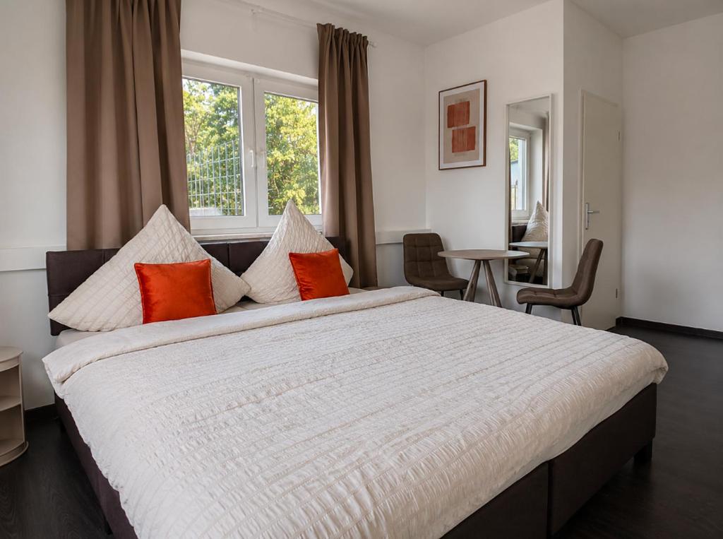 a bedroom with a large bed with orange and white pillows at BASE stay Erlangen in Erlangen