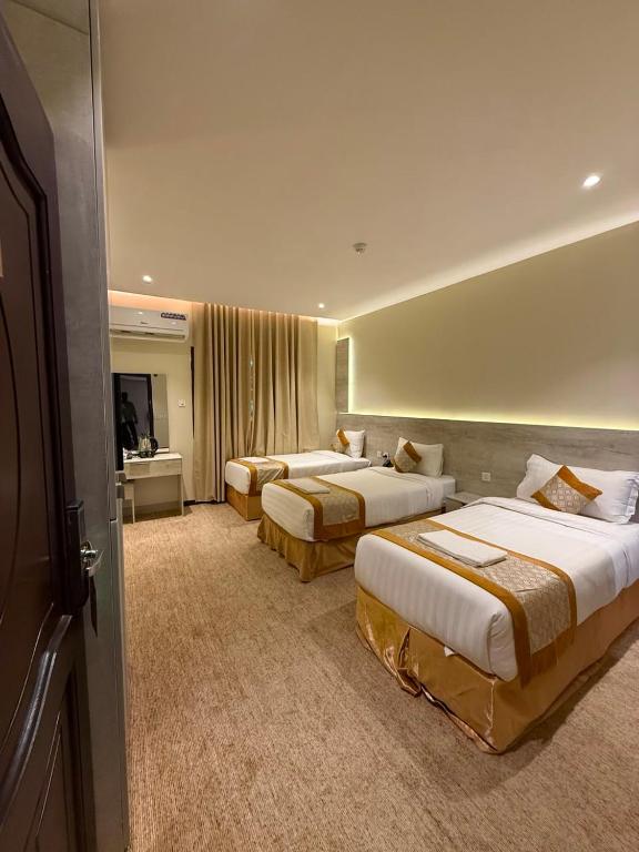a hotel room with three beds and a television at Johra International Hotel فندق جوهرة إنتر ناشونال in Medina