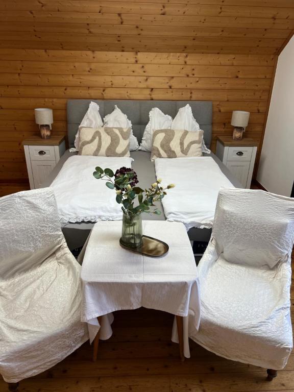 two beds with white sheets and a vase of flowers on a table at Mentebauer Traudi's Ferienhof in Rothenthurn