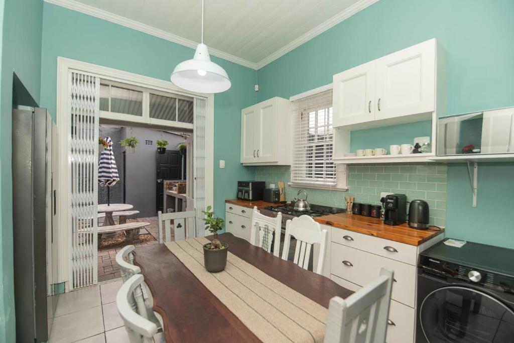 a kitchen with white cabinets and a wooden table at Crown Oak in Gqeberha