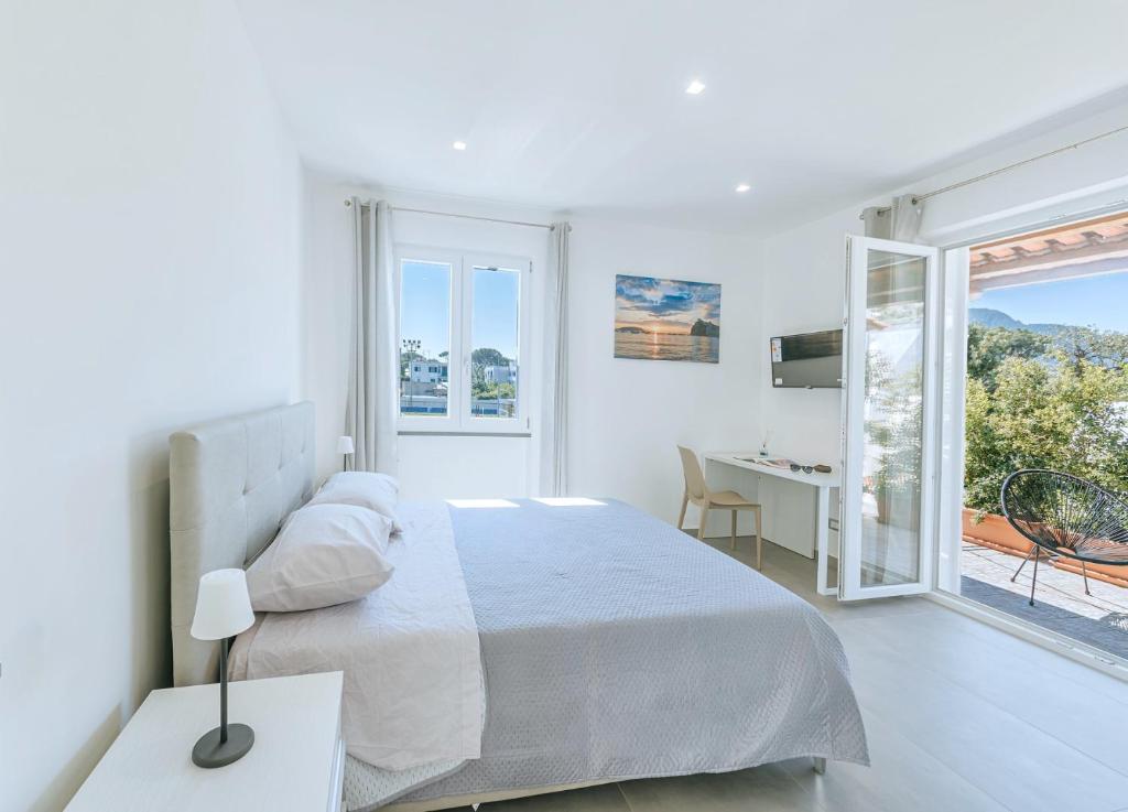 a white bedroom with a bed and a desk at Villetta Mami in Ischia