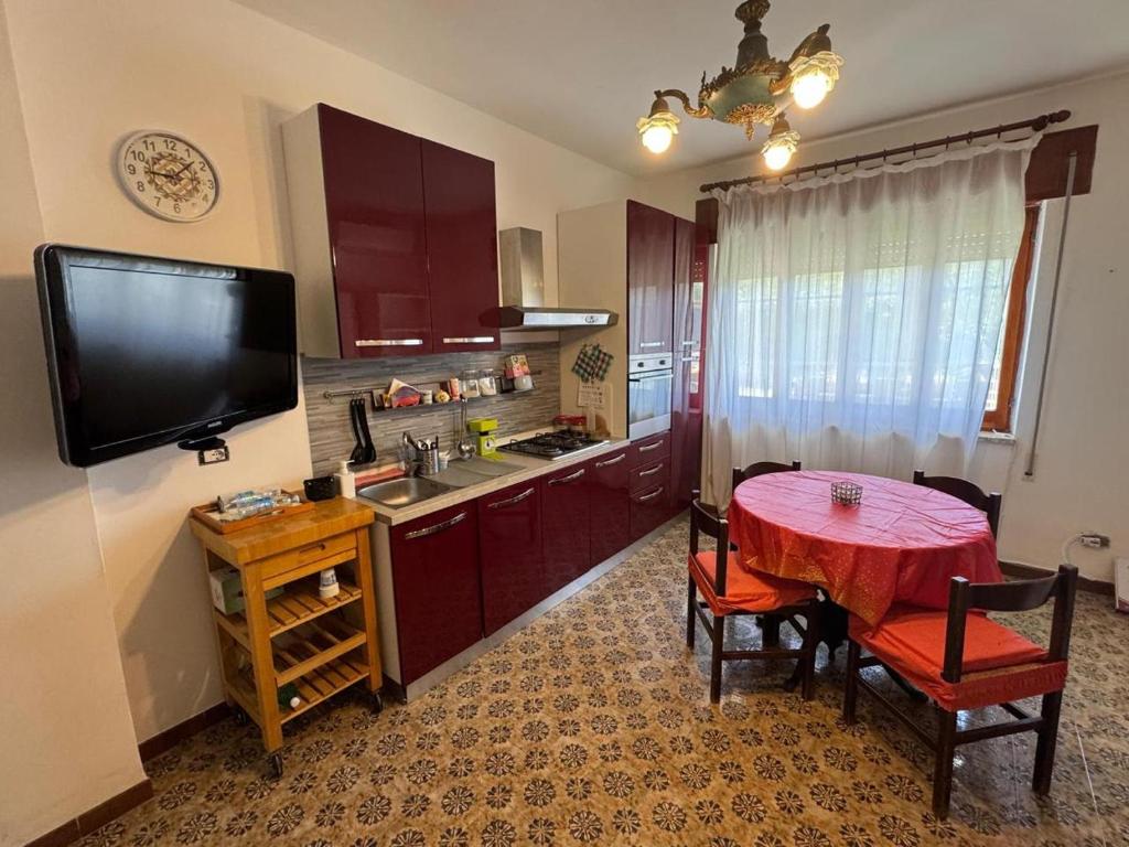 a kitchen with a red table and chairs and a television at Happy Rock in Formia