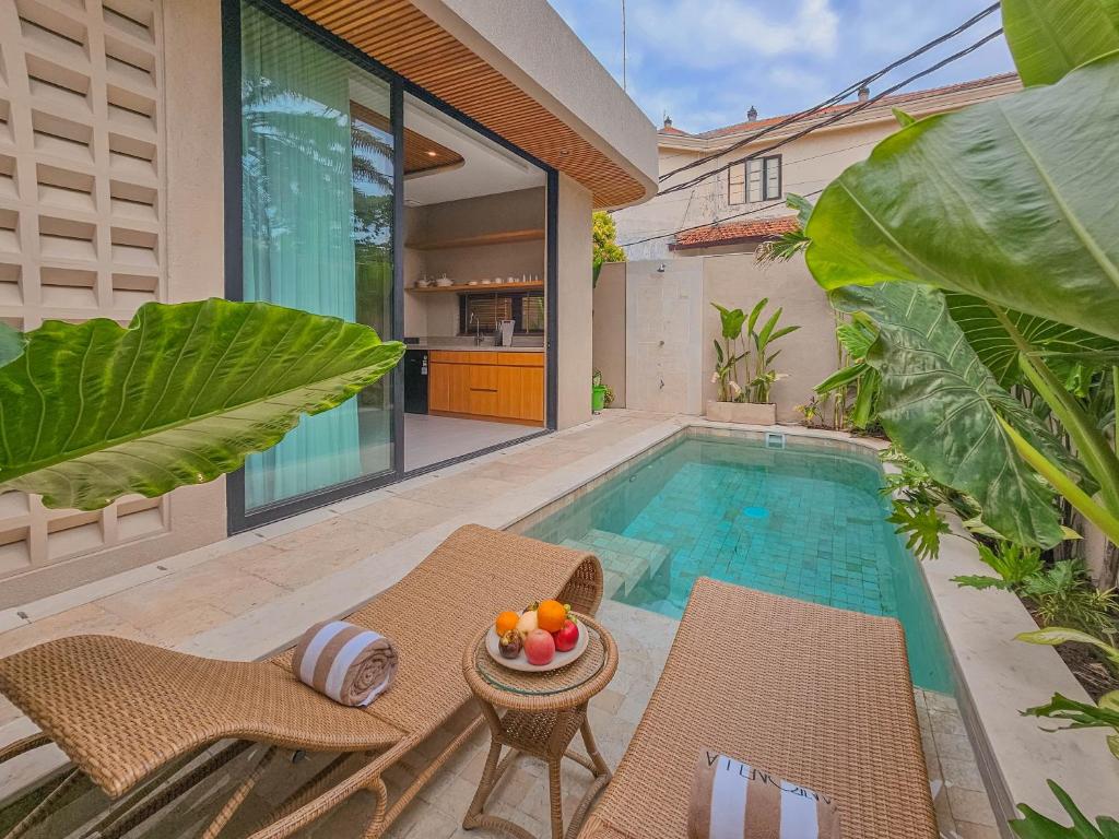 a swimming pool with two chairs and a table next to a house at Antonella De Rosa Villas in Nusa Dua