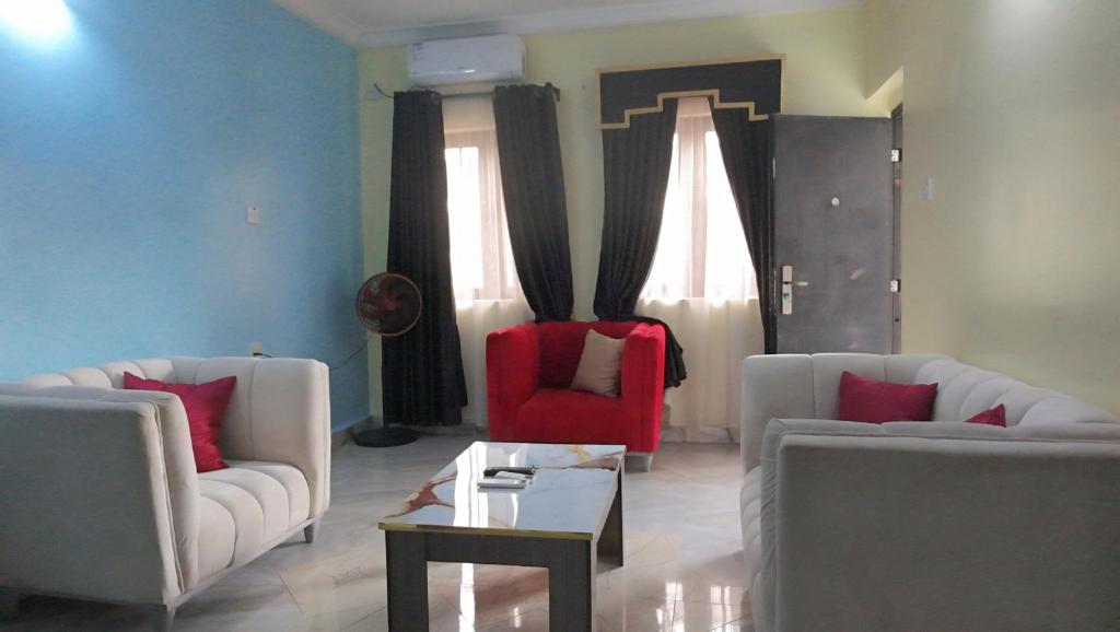 a living room with two white couches and a red chair at Awka Dawn Two Bed in Akwa