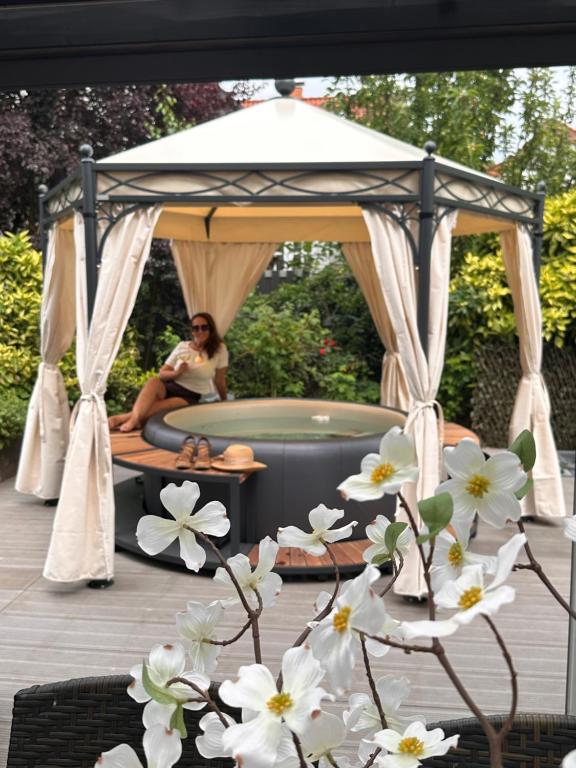 a woman sitting in a gazebo on a deck with white flowers at FeWo by HD mit Parkplatz, Wallbox, Wintergarten in Bad Salzuflen