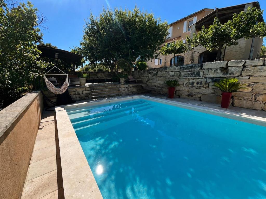 a swimming pool in a yard with a stone wall at Les Coustelines Piscine privée et Jacuzzi in Forcalquier