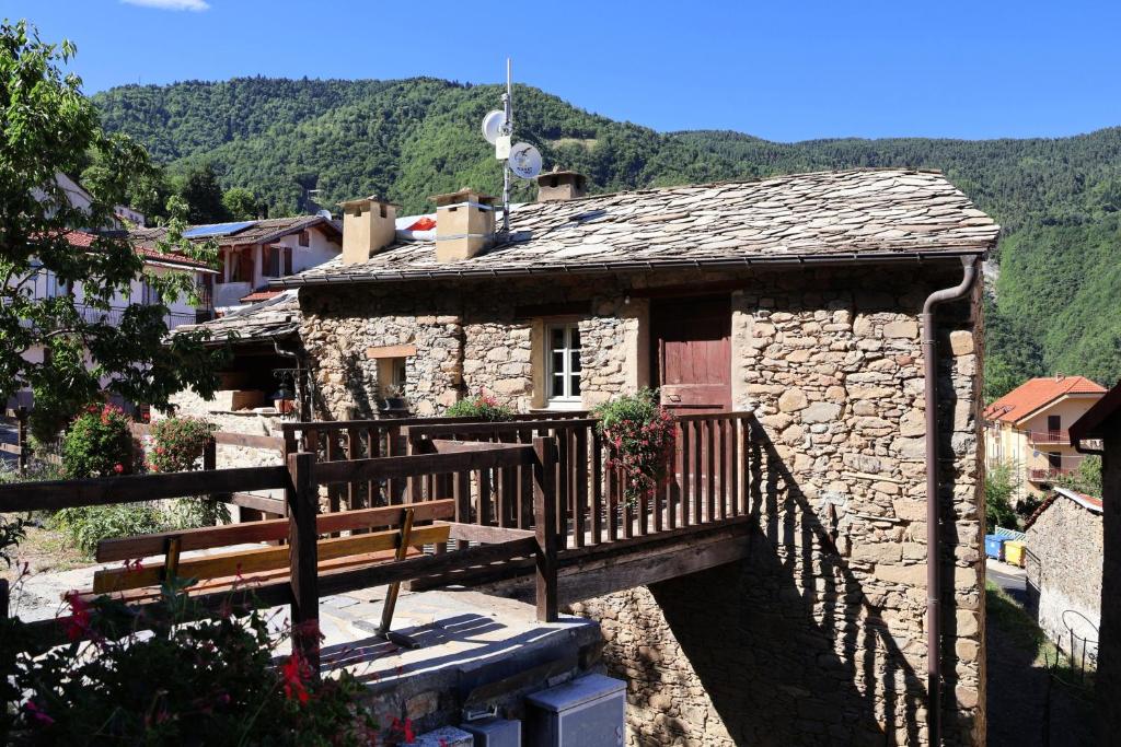a stone building with a bench and a balcony at Rifugio Ca' da Cardella in Mendatica