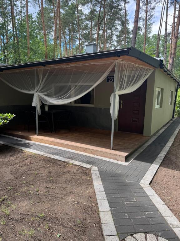a cabin with awning on a deck in the woods at Domek MajAmi in Turawa