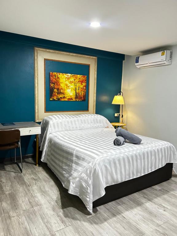 a bedroom with a bed and a desk and a painting at SkyLink Homes - Pattunaam - Airport Link & BTS Chidlom in Bangkok