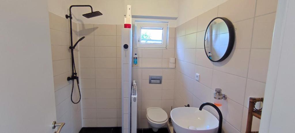 a bathroom with a toilet and a sink and a mirror at Apart Königseiche in Goldenstedt