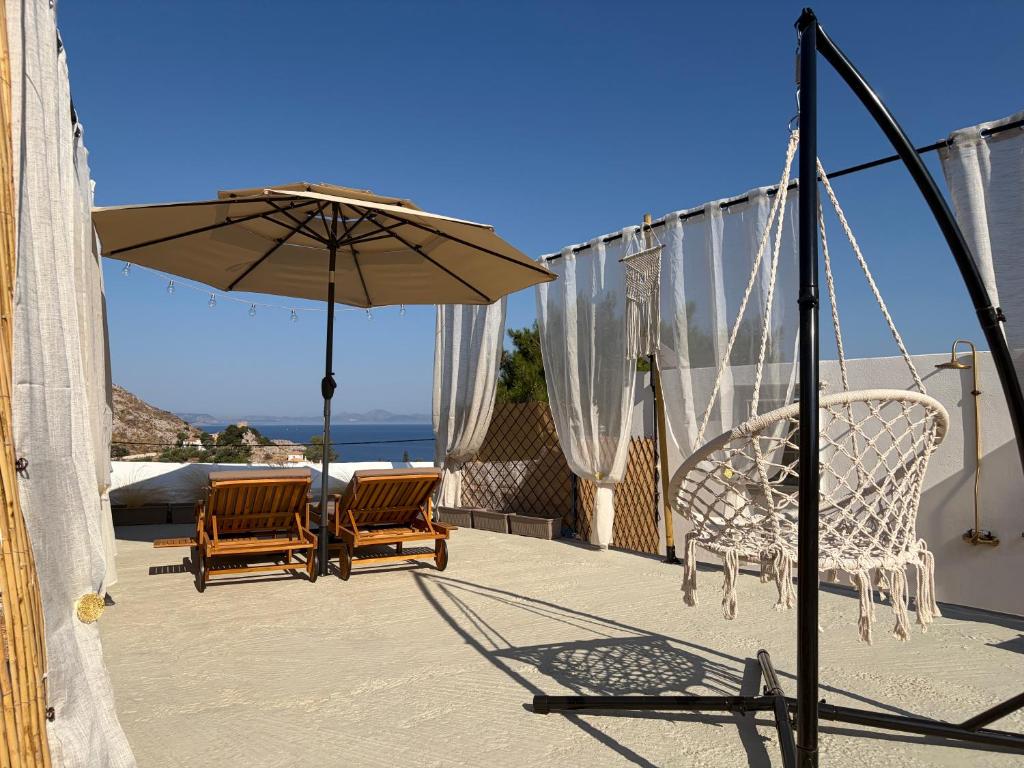 a patio with two chairs and an umbrella at Leonidas house hydra in Hydra