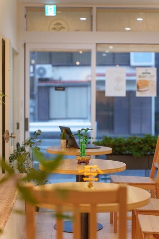 a group of tables and chairs in a room at Bonsai Cafe and Stay - B&B Dormitory in Tokyo