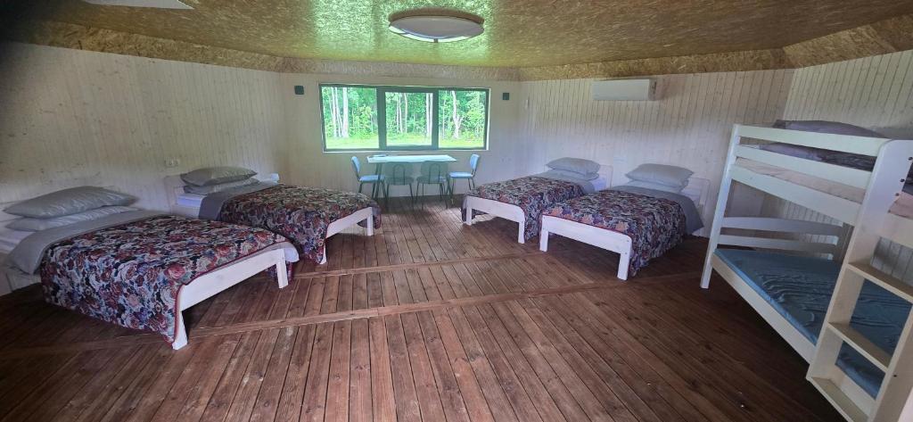 a room with four beds and a table and a window at Mäe Puhkemaja in Rosma