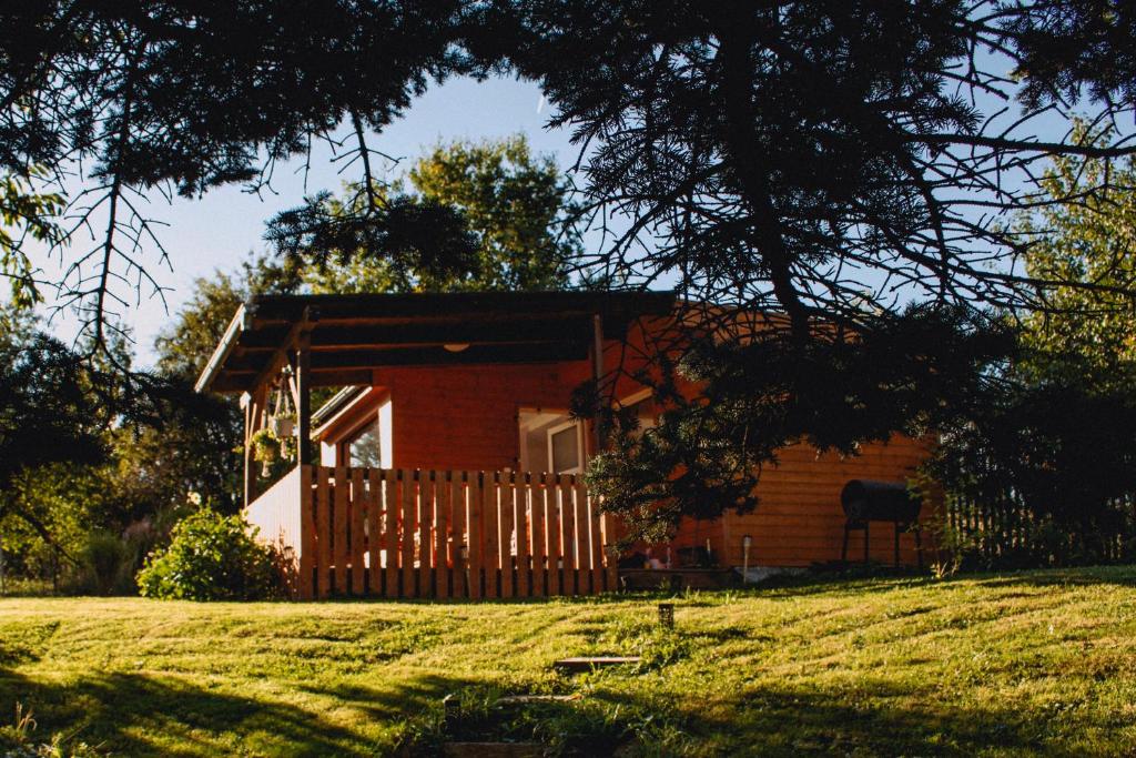 a small red house with a fence in a field at Statek ráj Netvořice, Tiny house and Farm Experience in Netvořice