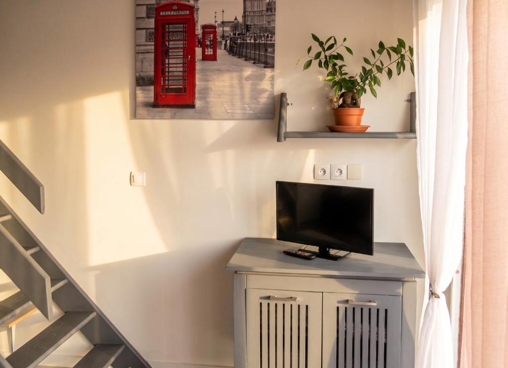 a tv sitting on a cabinet in a room with a staircase at Studio confortable à Pédernec - 27m² - Terrasse ensoleillée in Pédernec