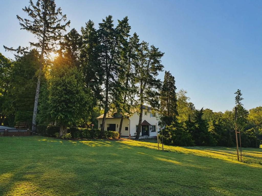 a white house with trees and a grass field at Csiszárhegyi Vadászház in Karád