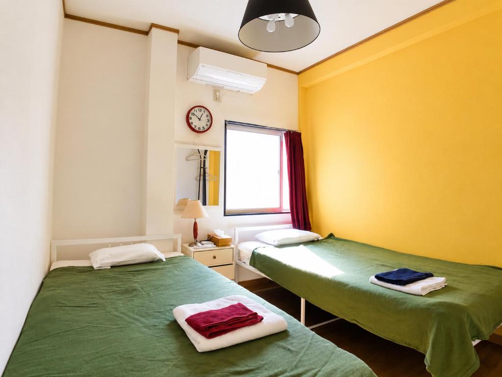 two beds in a room with yellow and green at Guesthouse LuLuLu 無料朝食&夕食ｶﾚｰ付き ﾛｰｿﾝ隣 街まで電車8分 in Kochi