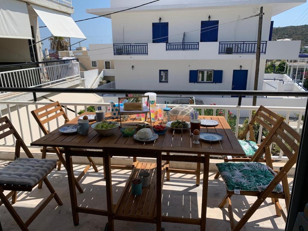 a wooden table on a balcony with chairs at Veranda Agia Marina in Agia Marina Aegina