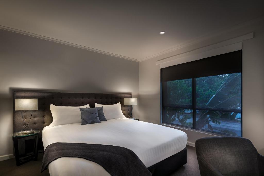 a bedroom with a large bed and a large window at Crest on Park in Melbourne