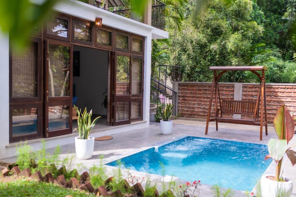 a backyard with a swimming pool and a swing at Tropical Grove in Polgolla