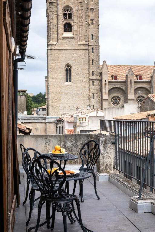 a table and chairs on a balcony with a clock tower at Rooftop privé - Clim - Place Carnot - Wifi in Carcassonne