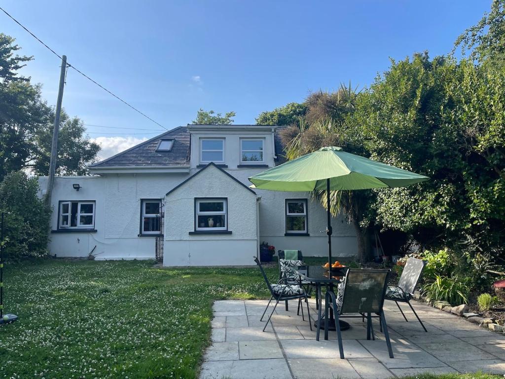 a table and chairs with an umbrella in front of a house at Dovetail Cottage in Wexford