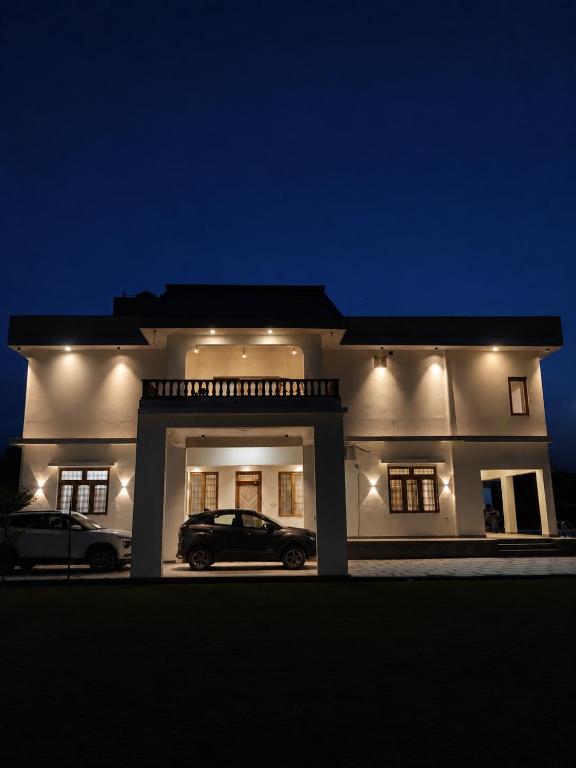 a white house with a car in front of it at Private Farm with Big Size Pool & 7 Rooms in Kukas in Jaipur