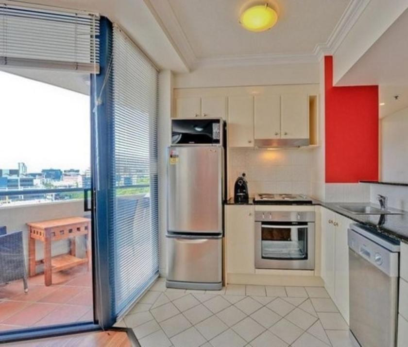 a kitchen with a stainless steel refrigerator and a table at Shevlin Apartments in Brisbane