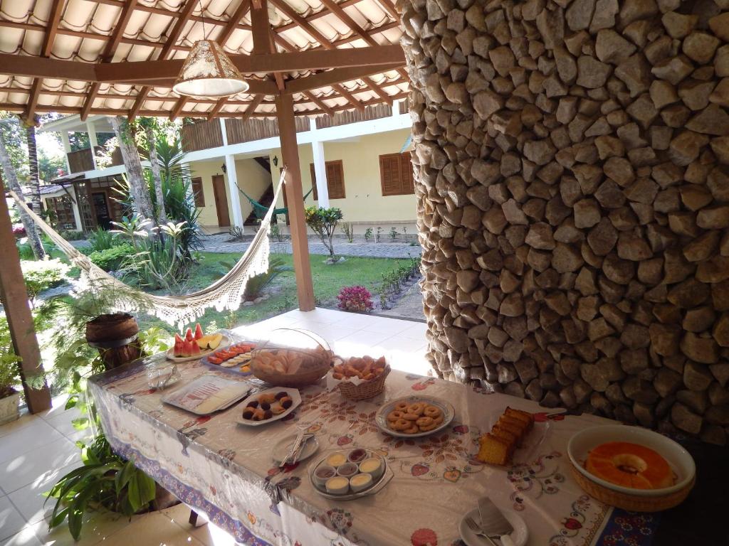 a table with plates of food on it next to a stone wall at Pousada Namuncurá in Arraial d'Ajuda