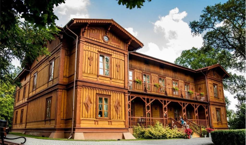 a large wooden building with a clock on it at Modrzewiowy Dworek in Mirzec