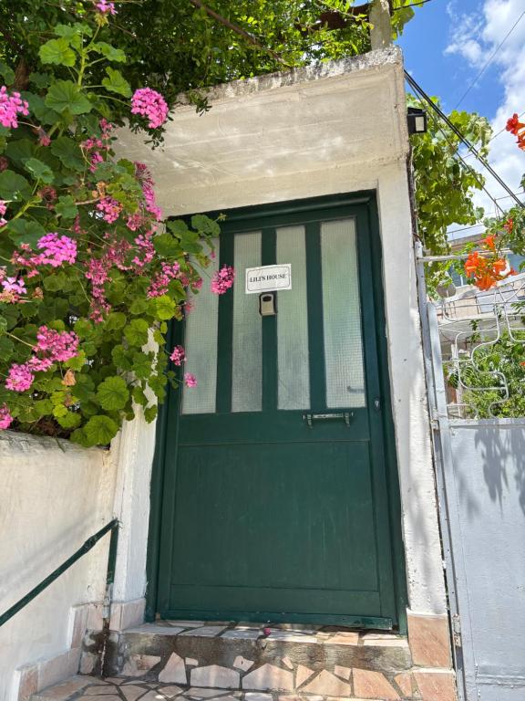 a green door with a sign on it next to pink flowers at Lili's House in Delvinë