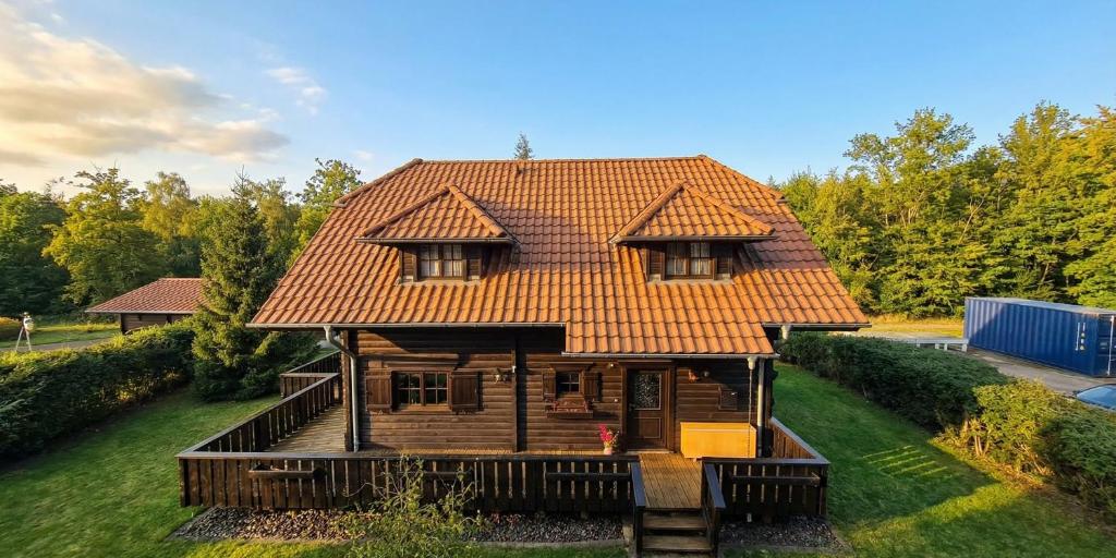 a wooden house with an orange roof on a yard at Ferienhaus John in Saarwellingen