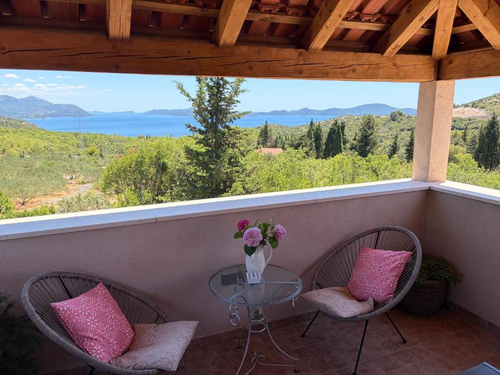 a balcony with two chairs and a table with a vase of flowers at Villa Fragola in Doli