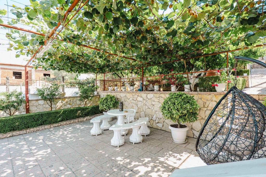 a patio with two white benches under a tree at Villa Kevin's in Sarandë