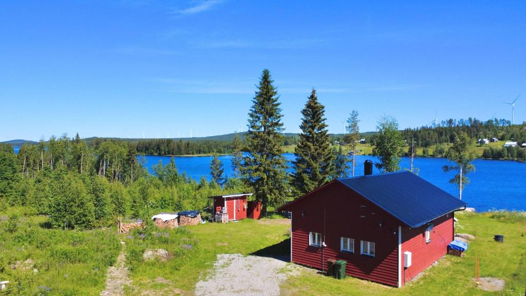 a red house in a field next to a lake at Sodra Fullsjön in Stugun