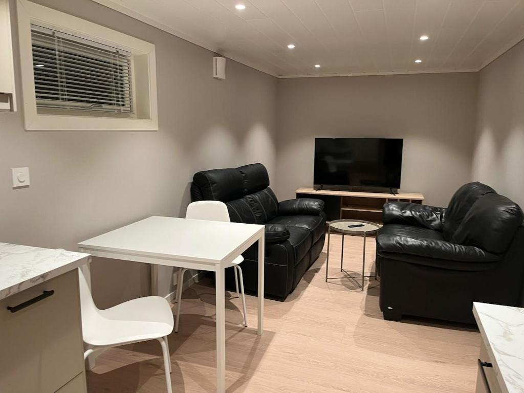 a living room with black leather furniture and a flat screen tv at Basement apartment in Tokheim